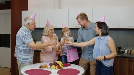 Mother,-father-and-grandparents-giving-gift-bag-for-child-girl.-Celebrating-birthday-anniversary