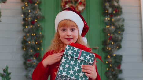 Happy-toddler-child-girl-kid-in-red-sweater-presenting-one-Christmas-gift-box,-stretches-out-hands