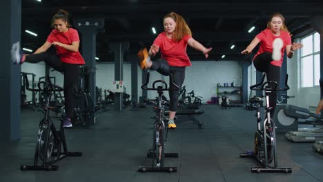 Healthy-Caucasian-group-of-women-exercising-workout-on-stationary-cycling-machine-bike-in-gym