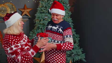 Abuela-Mayor-Presentando-Caja-De-Regalo-De-Navidad-Al-Abuelo,-Casa-Celebrando-El-Año-Nuevo-Juntos