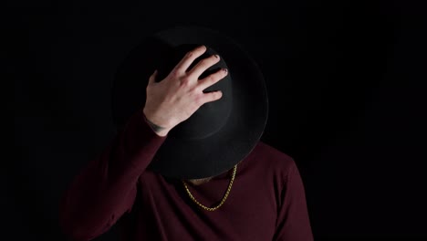 Portrait-of-seductive-smiling-young-man-in-trendy-stylish-clothes-wearing-hat-on-black-background