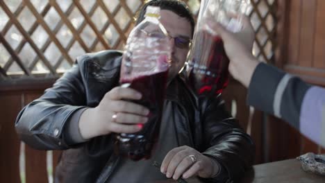 Two-men-sit-at-the-table-and-drink-beer-from-plastic-bottles.-Happy