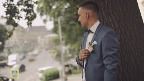 Un-Novio-Guapo-Se-Queda-Cerca-De-Un-árbol-En-La-Calle-De-La-Ciudad.-Día-De-La-Boda