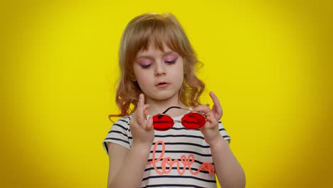 Portrait-of-funny-playful-blonde-child-girl-in-striped-t-shirt-wearing-sunglasses,-charming-smile