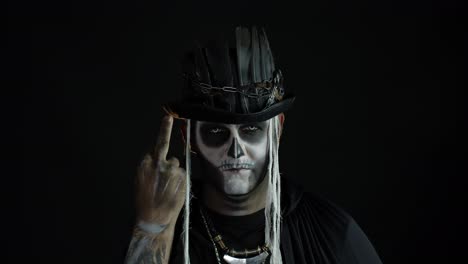 Finsterer-Mann-Mit-Totenkopf-Make-up,-Der-Grimassen-Schneidet-Und-Den-Mittelfinger-Zeigt.-Geste-Mit-Schlechtem-Benehmen.-Halloween