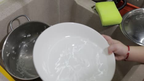 Child-washing-dishes-in-the-kitchen.-Close-up-of-girls-hands