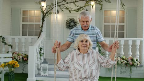 Pareja-De-Ancianos-Juntos-En-El-Patio-Delantero-De-Casa.-Hombre-Balanceándose-Y-Abrazando-A-Una-Mujer.-Familia-Madura-Feliz