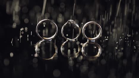 Anillos-De-Boda-Y-Compromiso-Sobre-Una-Superficie-De-Agua-Oscura-Brillando-Con-Luz