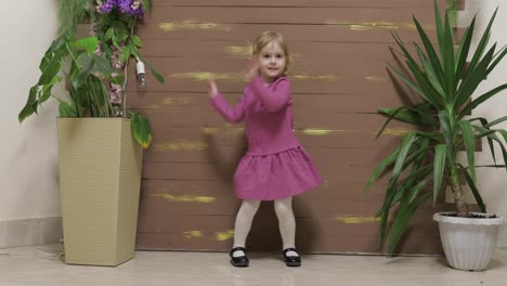 Little-child-dance-near-flowerpots-and-wooden-fence.-Feel-happy,-smiling