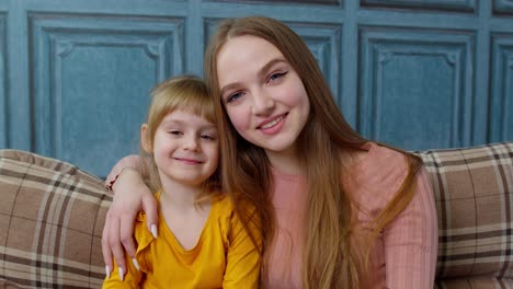 Portrait-of-satisfied-child-kid-daughter-with-young-mother,-hugging,-embracing,-showing-thumbs-up