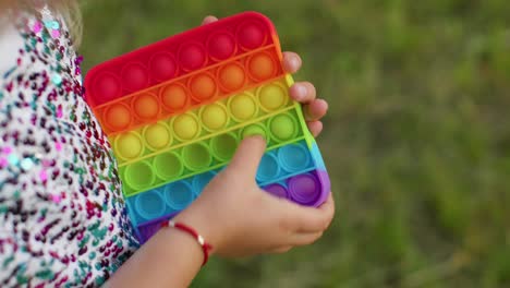 Child-girl-playing-colorful-squishy-silicone-bubbles-sensory-toy-simple-dimple-pop-it-game,-close-up