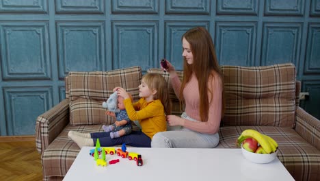 Mutter-Kümmert-Sich-Um-Tochter,-Mädchen-Bürstet-Haare-Im-Wohnzimmer,-Kind-Spielt-Mit-Spielzeugpuppe