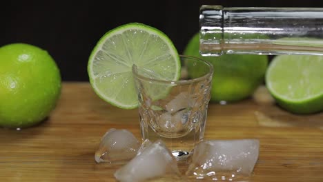 Wodka-Oder-Tequila-Aus-Einer-Flasche-In-Schnapsgläser-Mit-Eiswürfeln-Gießen