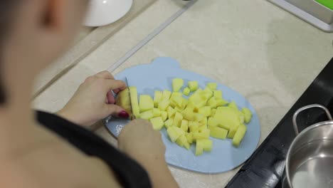 Woman-cutting-potato-on-the-blue-cutting-board