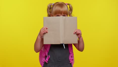 Graciosa-Niña-De-Escuela-Primaria-Con-Colas-De-Caballo-Con-Uniforme-Mirando-Mientras-Se-Esconde-Detrás-De-Un-Libro