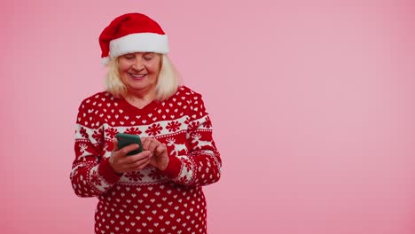 Abuela-Santa-Suéter-Navideño-Con-Teléfono-Móvil-Mostrando-Un-Lugar-Vacío,-área-De-Publicidad