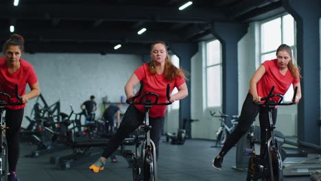 Group-of-girls-performs-aerobic-training-workout-cardio-routine-on-bike-simulators,-cycle-training