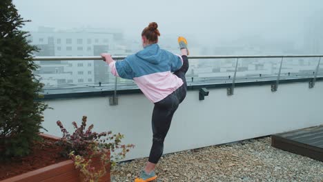 Fit-girl-making-workout-cardio-training-exercises-outdoors-squats-yoga-stretching-exercising-on-roof