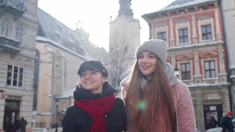 Dos-Mujeres-Turistas-Sonrientes-Caminando-Juntas-Por-Las-Calles-De-La-Ciudad,-Una-Pareja-Familiar-Hablando,-Abrazándose