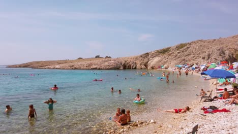 Croacia,-Isla-De-Krk,-Playa-De-Stara-Baška-Zala,-Vídeo-Panorámico-A-Través-De-La-Vívida-E-Impresionante-Bahía-Llena-De-Turistas