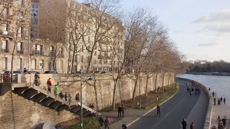 Orilla-Del-Río-Sena-Con-Peatones-Caminando-Y-Corriendo-Tranquilamente-En-París,-Francia