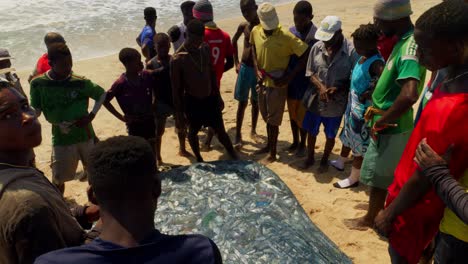 Hombres-Africanos-Felices-En-Una-Playa-Con-Una-Red-De-Pesca-Llena-De-Pescado-Fresco