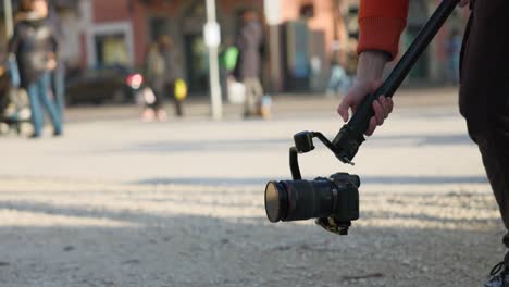 Videopgrapher-using-new-modern-DJI-RS3-stabilizer-gimbal-with-professional-camera-mounted-along-city-street-of-Mantua-in-italy