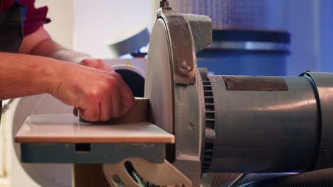 Artisan-sanding-wooden-object-on-disc-sander-in-assembling-shop