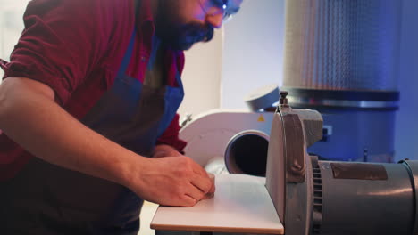 Cabinetmaker-working-in-joinery,-guiding-wood-against-grinding-machine,-close-up