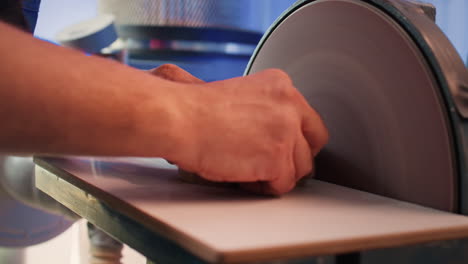 Artisan-sanding-wooden-object-on-disc-sander-in-assembling-shop