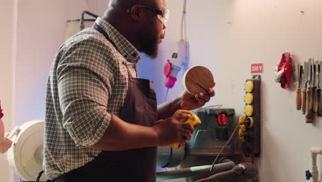 Man-in-studio-using-sandpaper-for-sanding-wooden-surface