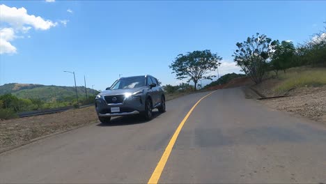 nissan-x-trail-driving-on-street-between-trees-gravel-street-,-compact-crossover-SUV