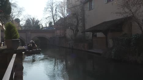 Motorboat-navigating-tourists-through-La-Lauch-river-flowing-through-the-medievil-town-of-Colmar,-France