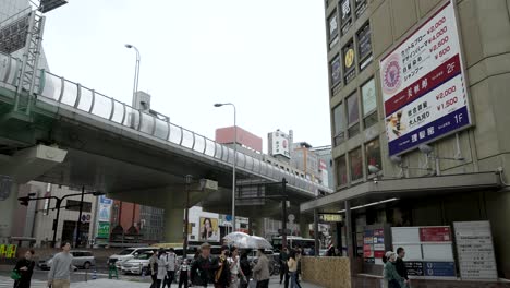 View-Of-Highway-Overpass-Above-Sennichimae-Dori-In-Namba,-Osaka-With-People-Walking-Past-On-Overcast-Day