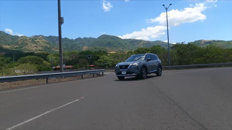 nissan-x-trail-driving-on-street-between-trees,-gravel-street-compact-crossover-SUV