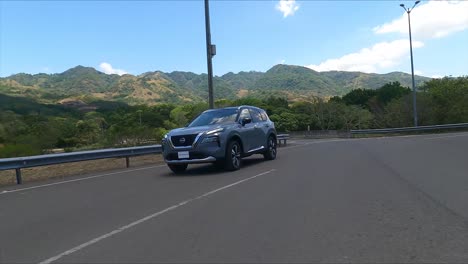 gravel-street,-nissan-x-trail-driving-on-street-between-trees,compact-crossover-SUV