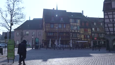 Gente-Caminando-Por-Una-Plaza-Peatonal-De-Adoquines-Con-Tradicionales-Edificios-Medievales-Y-Renacentistas-Tempranos-Con-Entramado-De-Madera