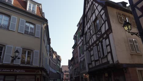 Hermosos-Edificios-Arquitectónicos-Con-Entramado-De-Madera-En-La-Ciudad-Medieval-De-Colmar,-Francia,-Con-Tiendas-En-La-Planta-Baja.