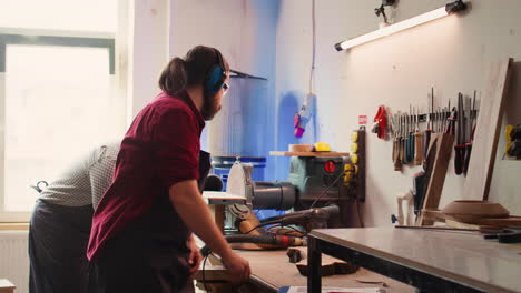 Craftsperson-uses-angle-grinder-on-wood-after-checking-schematics