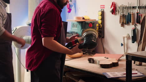 Craftsperson-uses-angle-grinder-on-wood-after-checking-schematics