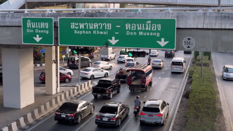 View-from-behind-of-a-slow-moving-traffic-at-a-busy-intersection-in-the-middle-of-the-city-of-Bangkok,-Thailand