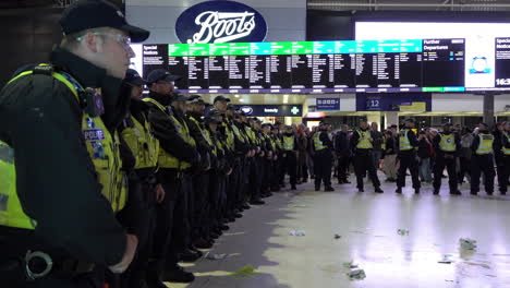 Polizeibeamte-Aus-Der-Metropolregion-Und-Der-Britischen-Transportpolizei-Rücken-In-Absperrlinien-Vor,-Um-Einen-Pro-Palästina-Sitzprotest-Im-Bahnhof-Von-Waterloo-Zu-Räumen