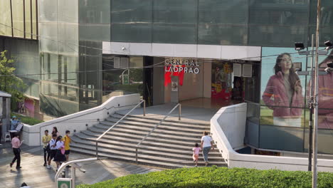 Passersby-passing-by-a-shopping-center,-while-others-are-going-inside-the-mall,-in-a-business-center-in-Bangkok,-Thailand