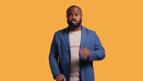 Stern-man-doing-stop-hand-gesture-sign,-studio-background