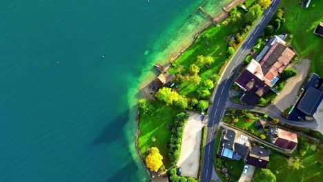 Vista-Aérea-Sobre-Edificios,-Una-Carretera-Y-Colores-De-Otoño-En-La-Costa-Del-Lago-Attersee,-Austria