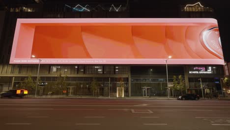 Time-lapse-of-the-largest-LED-Billboard-wall-in-downtown-Los-Angeles-california-showing-marketing-ads-along-car-traffic-and-traffic-lights-at-night-time---frontal-view