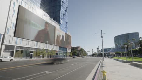 Time-lapse-of-the-largest-LED-Billboard-wall-in-downtown-Los-Angeles-california-showing-marketing-ads-along-car-traffic-and-traffic-lights-at-day-time---long-angle