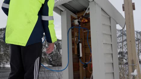 Enrollando-El-Cable-Del-Vehículo-Eléctrico-En-Un-Almacenamiento-Ordenado,-Invierno