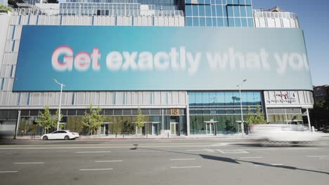 Time-lapse-of-the-largest-LED-Billboard-wall-in-downtown-Los-Angeles-california-showing-marketing-ads-along-car-traffic-and-traffic-lights-at-day-time---frontal-view