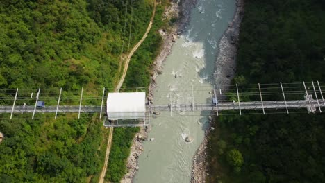 Toma-Aérea-De-Arriba-Hacia-Abajo-De-Puenting-En-Un-Puente-Sobre-El-Río-En-Pokhara,-Nepal